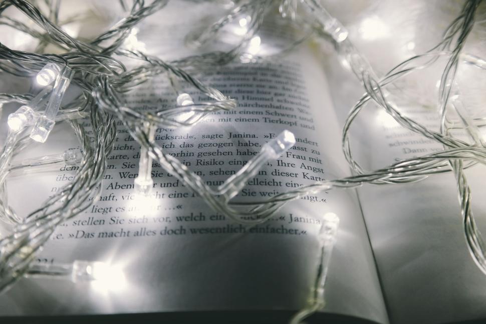 Free Image of Open book under fairy lights creating a cozy ambiance 