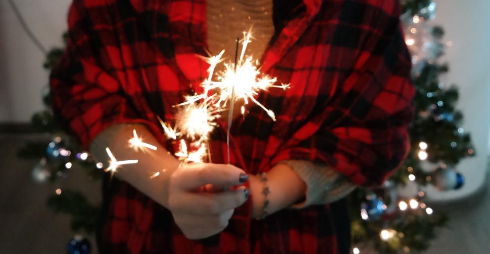 Free Image of Person holding sparklers with festive background decor 