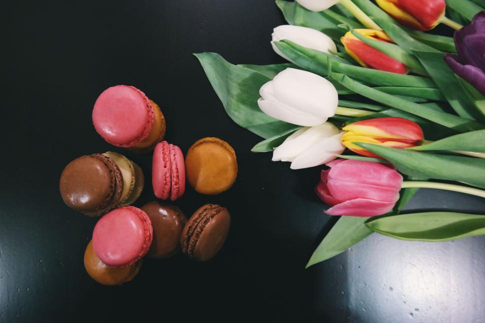 Free Image of Colorful macarons and tulips resting on a dark surface. 