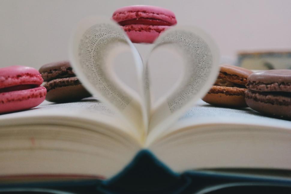 Free Image of Heart-shaped book page adorned with colorful macarons. 