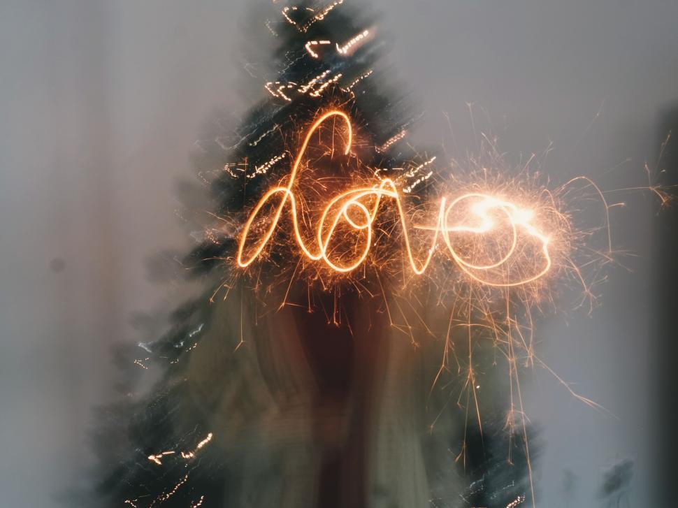 Free Image of Sparkler writing love in front of Christmas tree 