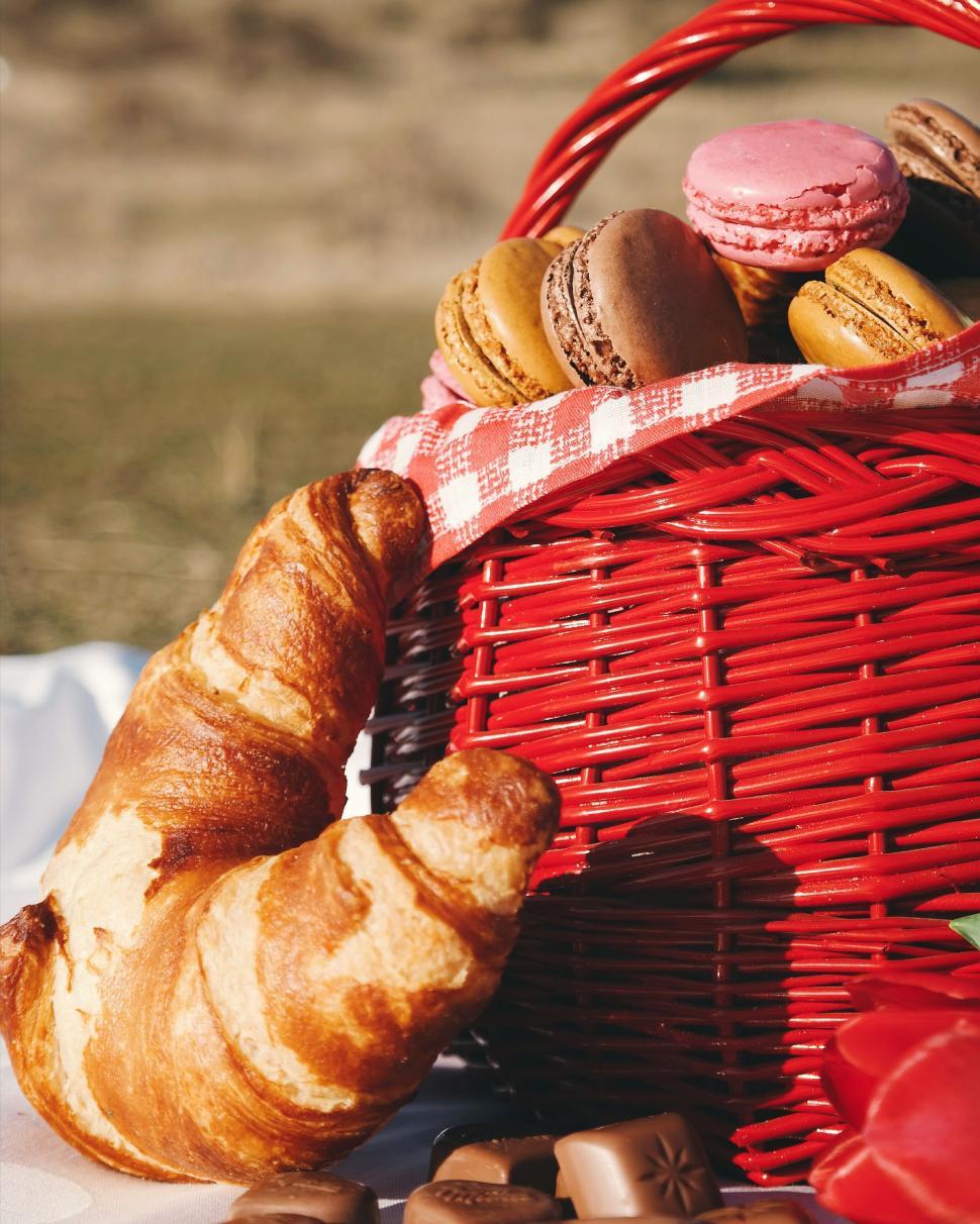 Free Image of Red basket with croissants and macarons outdoors 