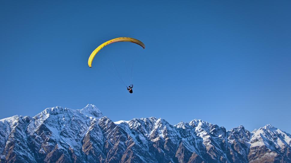 Free Image of Paraglider flying high above snowy mountain peak 