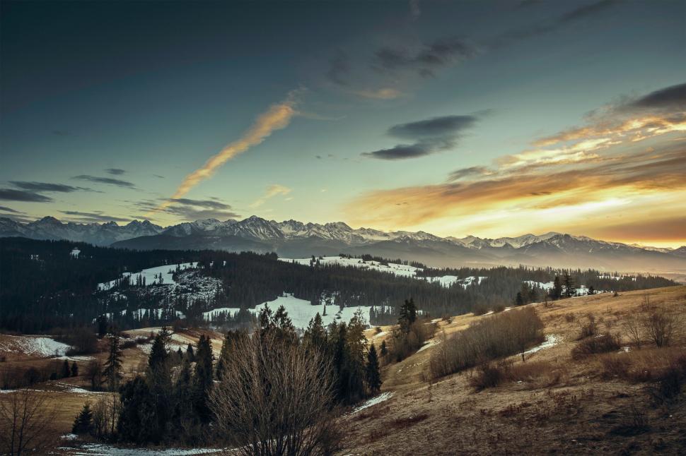 Free Image of Snow-covered landscape with mountain range at sunset. 