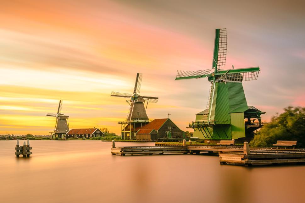 Free Image of Three windmills at sunrise with colorful sky reflection 