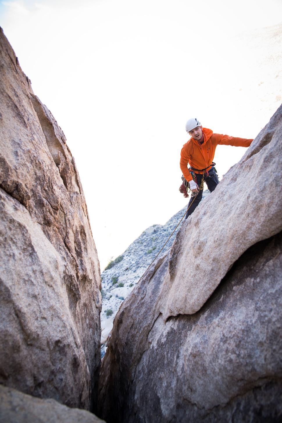 Free Image of Person rock climbing on a mountain in bright gear 