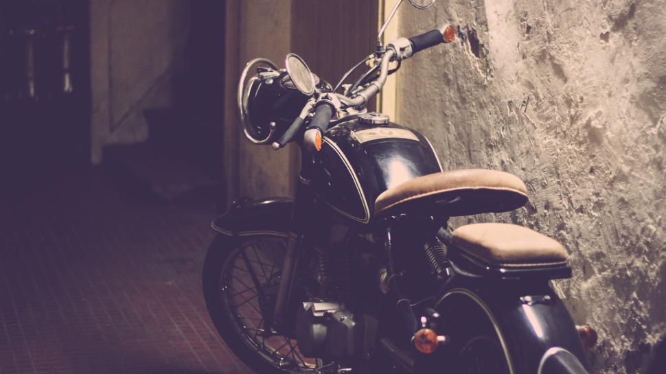 Free Image of Vintage motorcycle parked against a weathered wall indoors. 