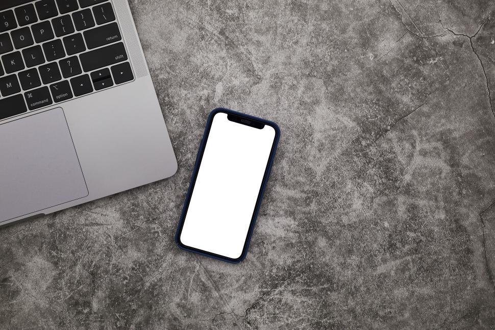 Free Image of Laptop and smartphone on a minimalist concrete workspace. 