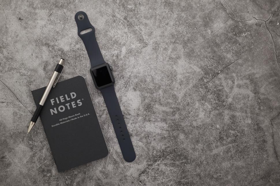 Free Image of Black notebook pen and smartwatch on gray surface 