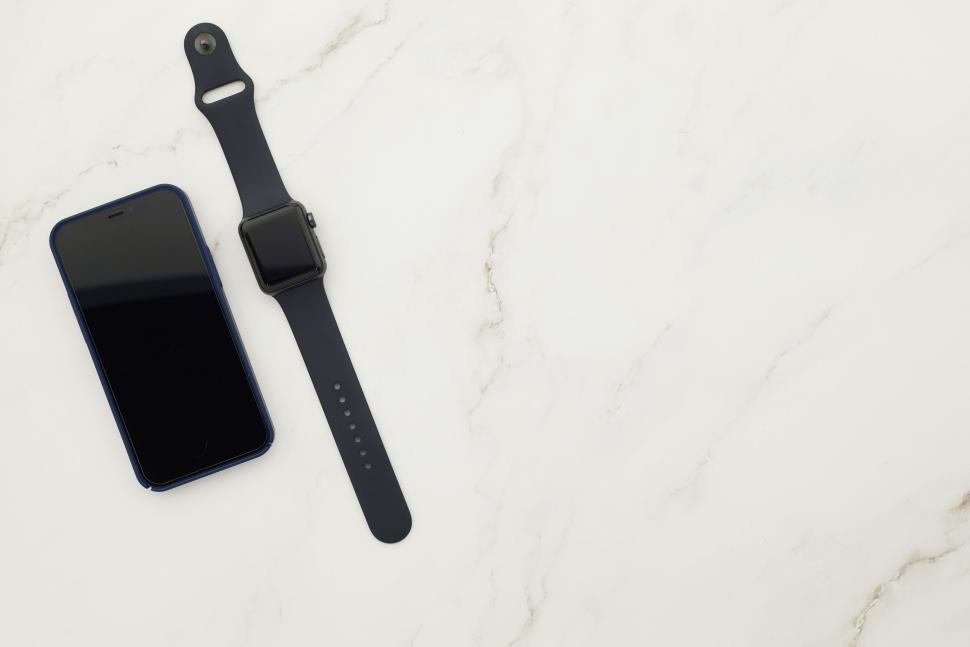Free Image of Smartphone and smartwatch on white marble surface 