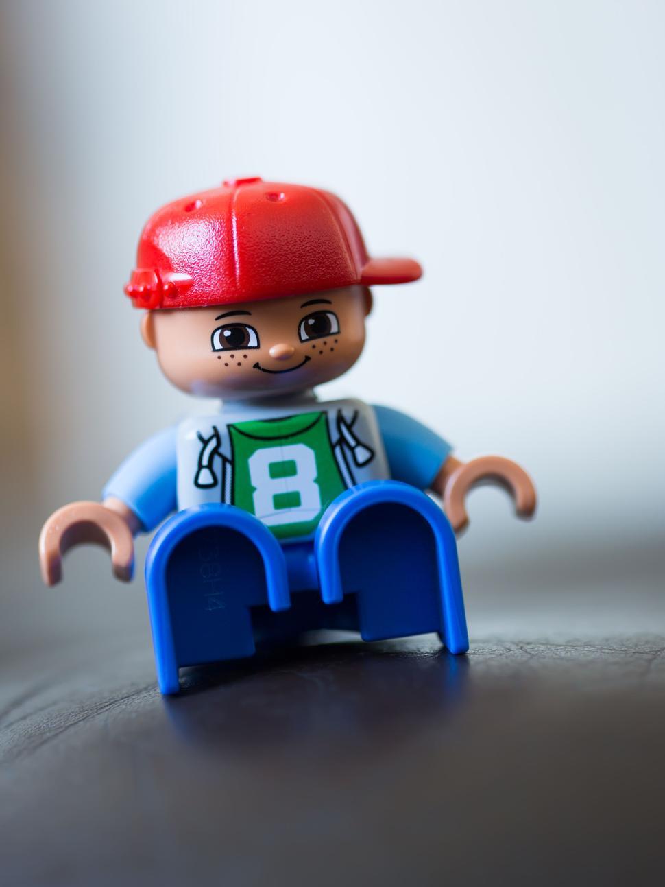 Free Image of Toy figurine sitting with casual attire and a red cap. 