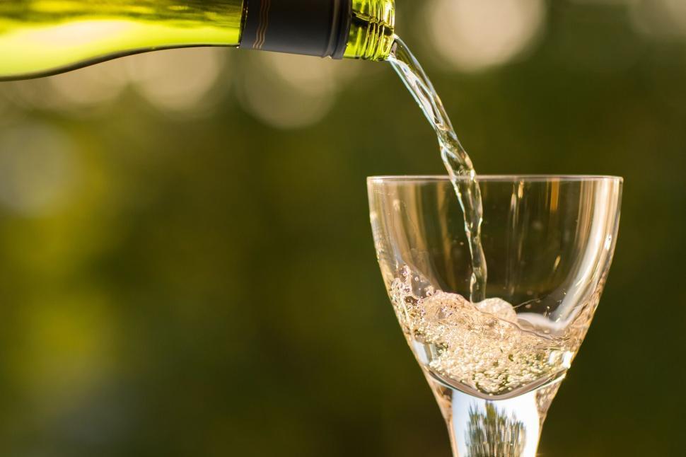 Free Image of Wine being poured into a glass with blurred green background. 