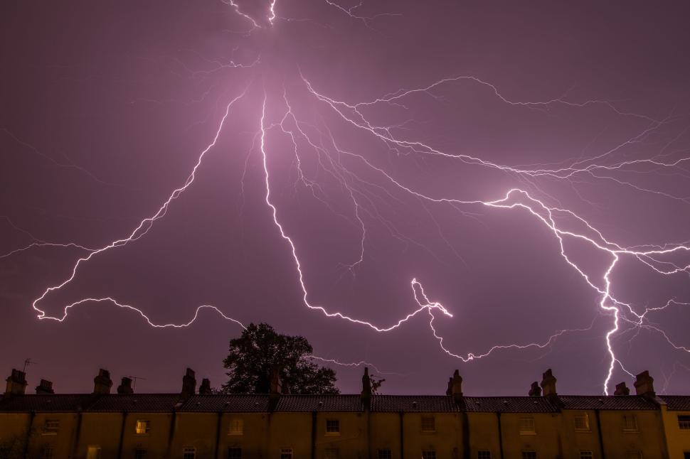 Free Image of Dramatic lightning strike over residential rooftops at night 