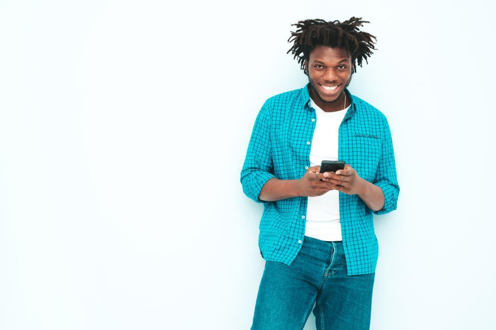 Free Image of Man smiling and using smartphone in blue shirt. 