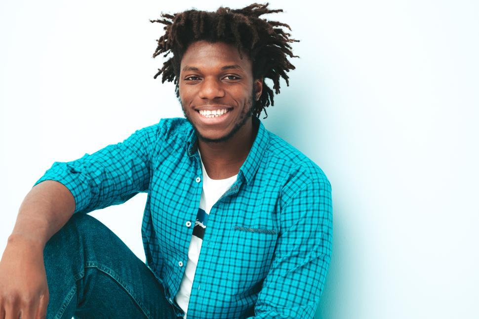 Free Image of Man sitting cross-legged smiling at camera casually. 