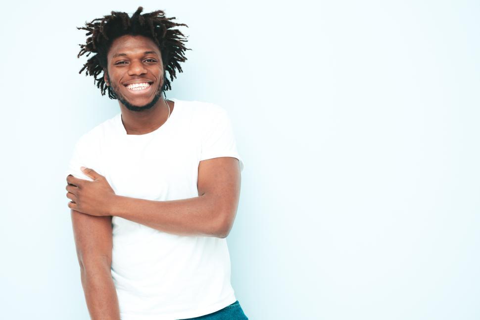Free Image of Man wearing white T-shirt smiling with arm crossed. 