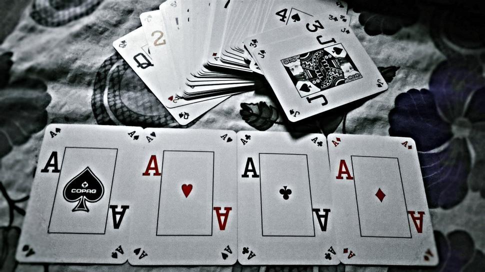 Free Image of Four aces and a joker card spread on a patterned surface 