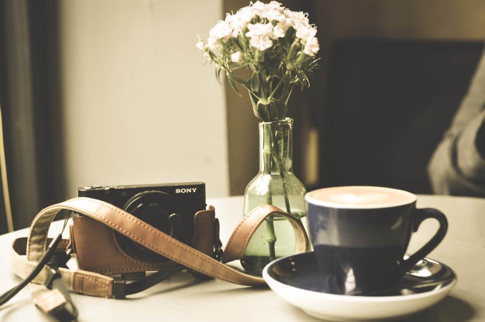 Free Image of Cup of coffee with camera and flowers on cozy table 