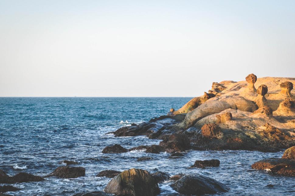 Free Image of Rocky coastal landscape with waves crashing on the shore. 