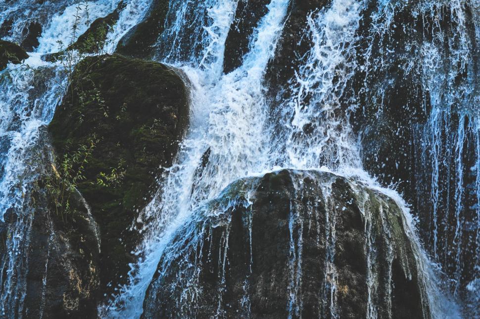 Free Image of Rushing waterfall over moss-covered rocks and boulders 