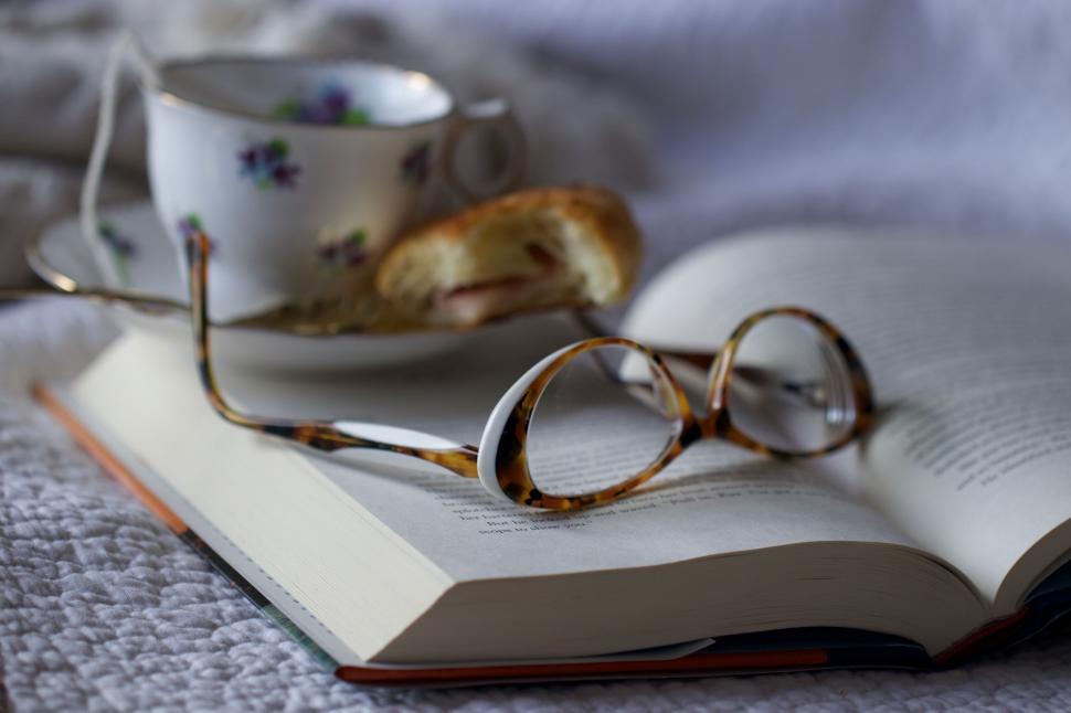 Free Image of Open book with glasses and tea on white blanket 