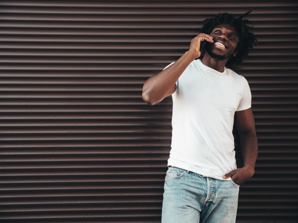 Free Image of Man in white t-shirt talking on phone, casual pose. 