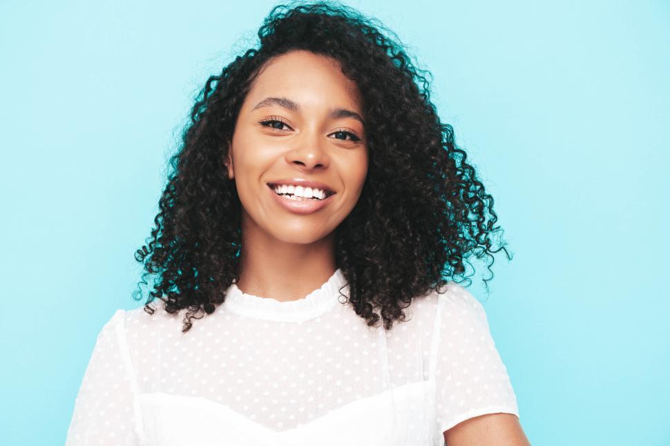 Free Image of Smiling woman in white dress with blue background close-up 
