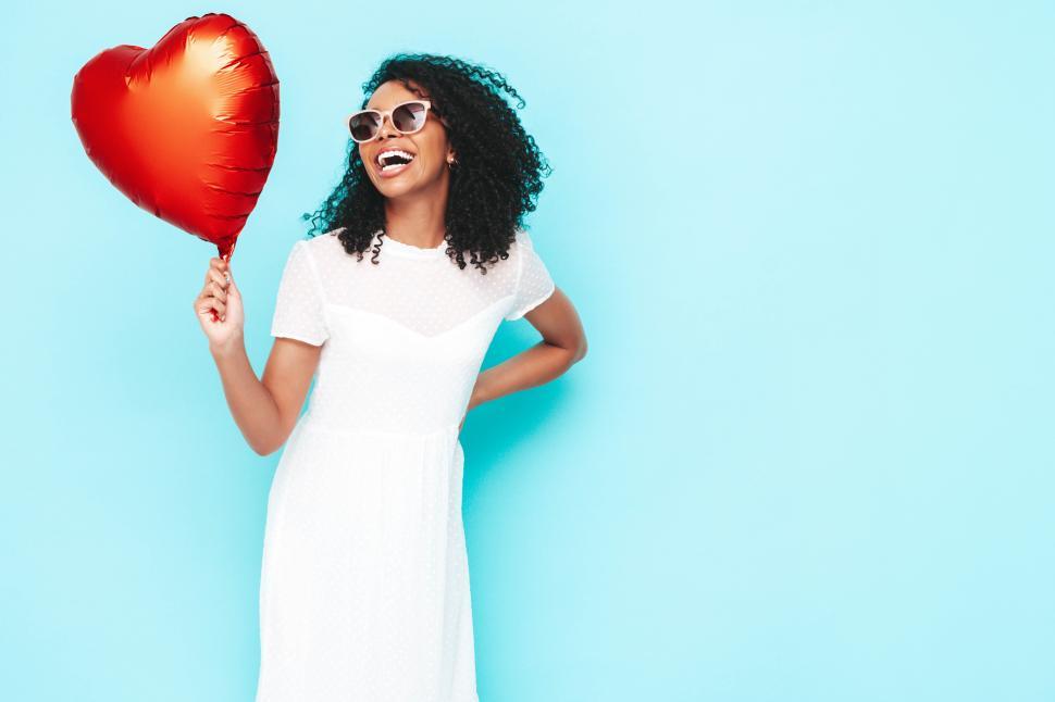 Free Image of Woman in white dress holding a heart-shaped balloon. 