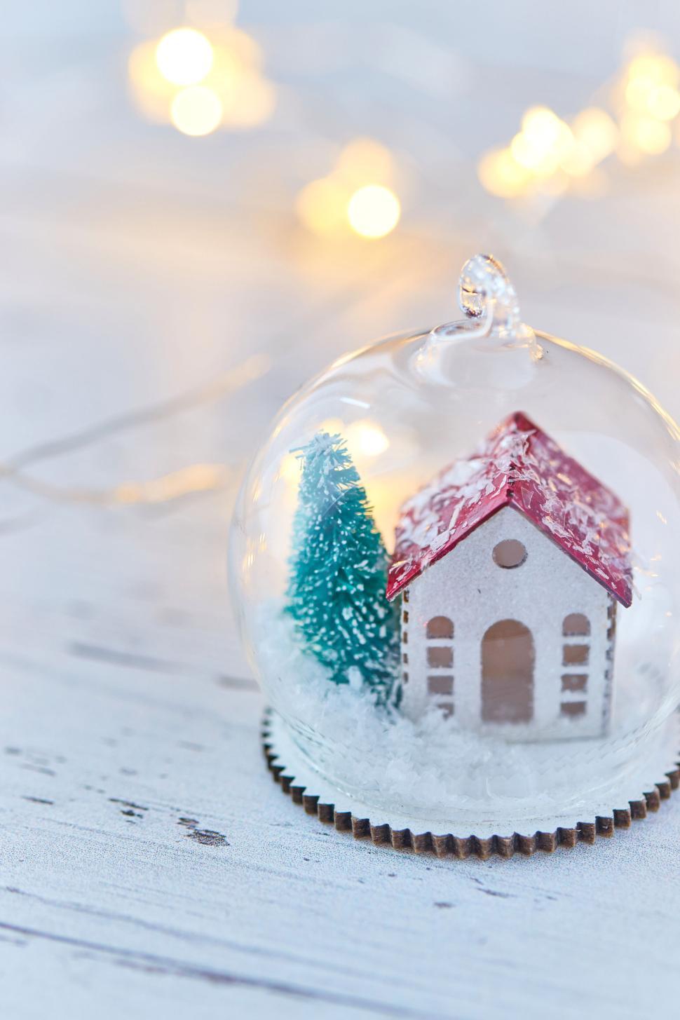 Free Image of Miniature house in a glass globe with festive lights. 