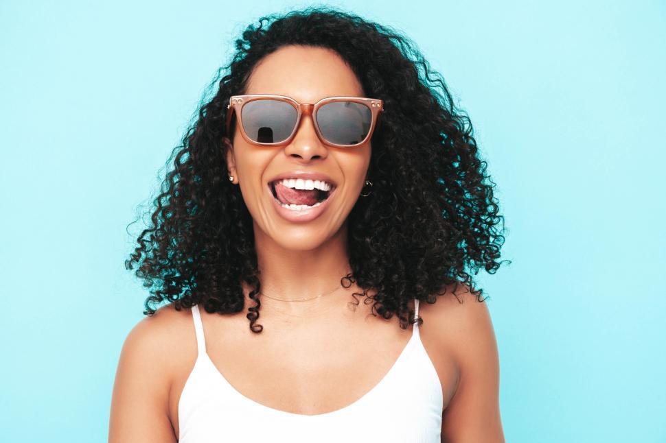 Free Image of Close-up of smiling woman with curly hair and sunglasses 