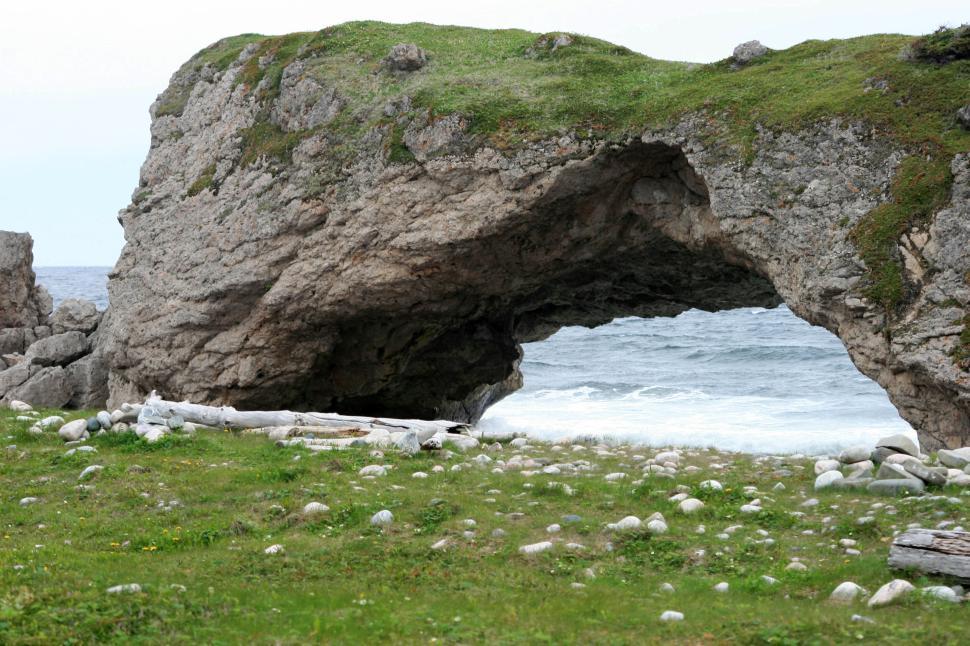 Free Image of Natural rock arch by the seaside on a grassy shore 