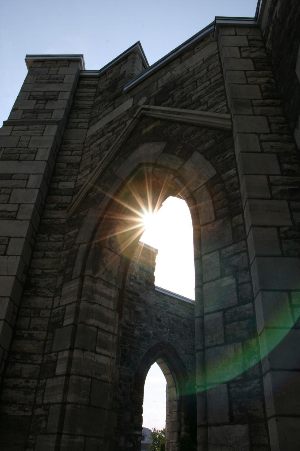 Free Image of Sunlight peeking through the arches of a stone structure 