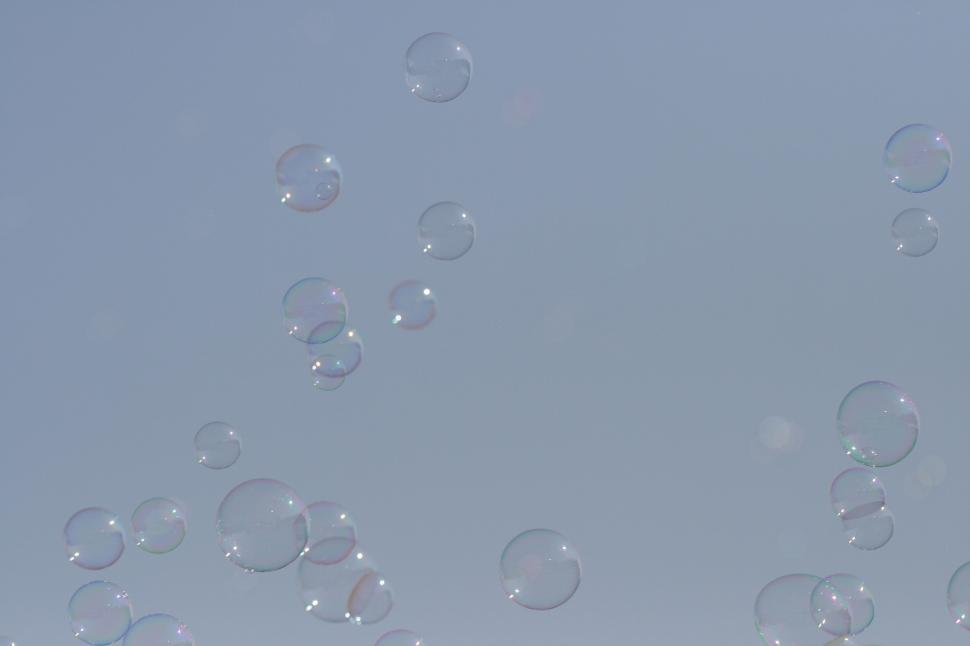 Free Image of Multiple soap bubbles floating against a clear sky background 