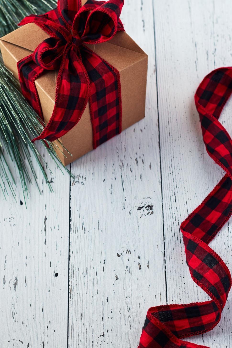 Free Image of Rustic Christmas gift box with red plaid ribbon on paint 