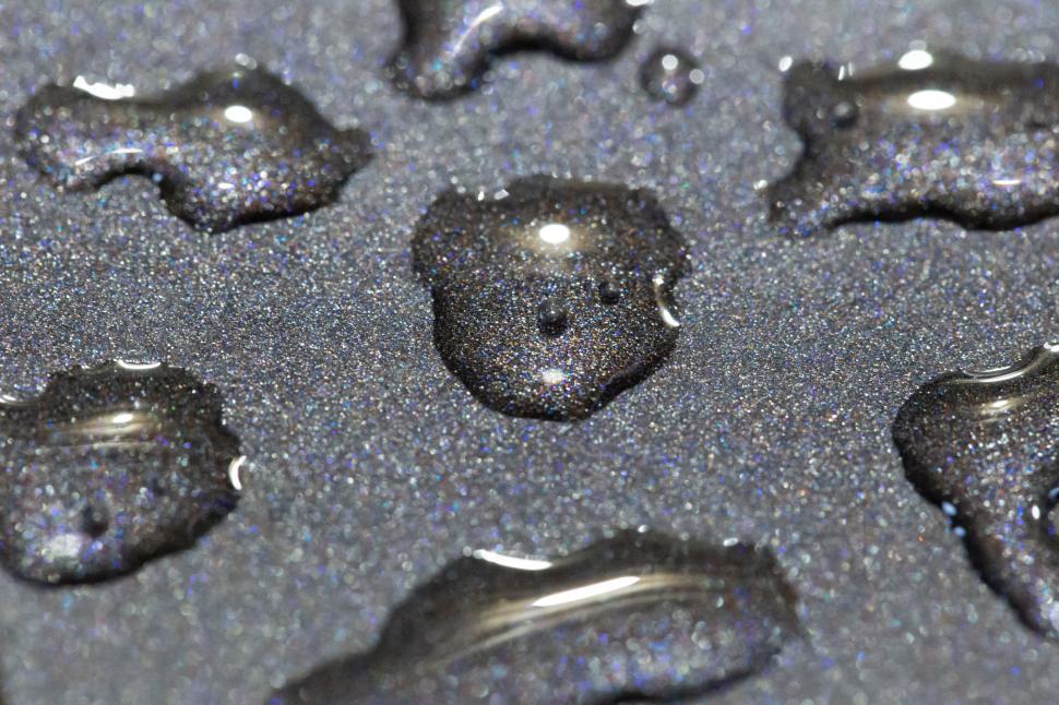 Free Image of Water droplets on a dark surface creating shapes 