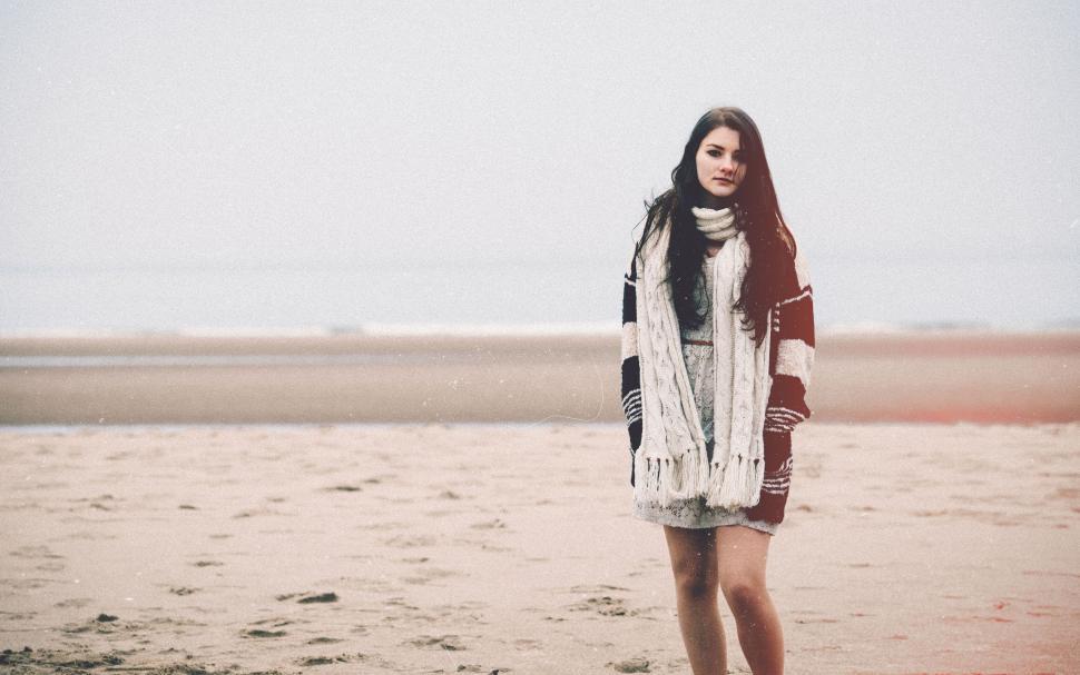 Free Image of Woman on the beach in warm clothing with scarf. 