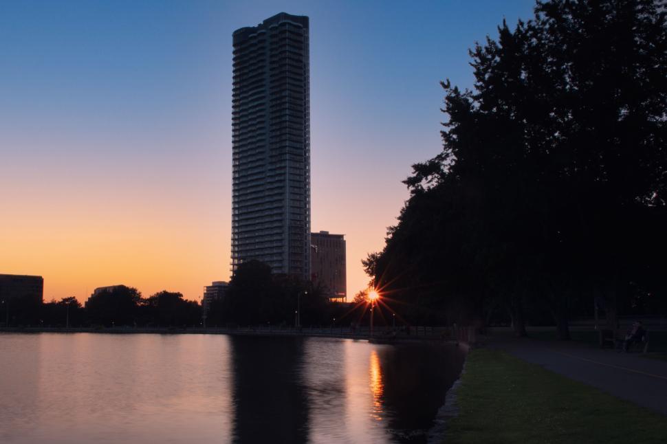 Free Image of Tall building with sunset reflection by the lake 
