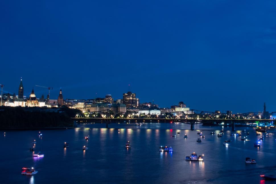 Free Image of Night view of city skyline with illuminated boats on water 