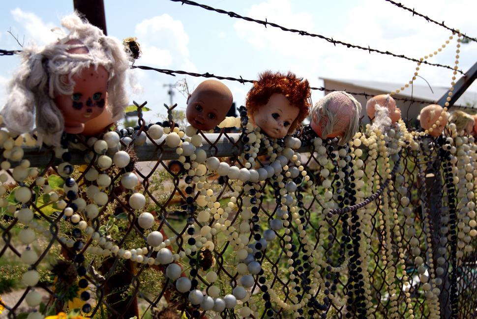Free Image of Baby Doll Heads stuck on a fence 