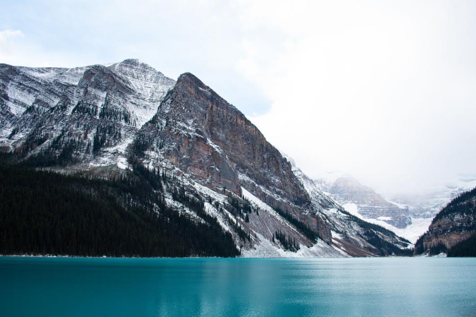 Free Image of Majestic snow-capped mountain overlooking clear blue lake. 