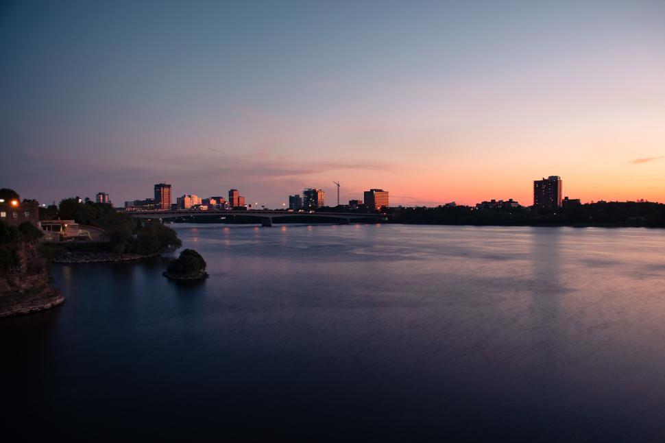 Free Image of City skyline at dusk with water reflection and bridge 