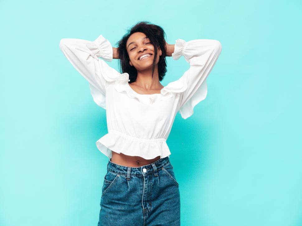 Free Image of Carefree woman in white blouse enjoying blue backdrop. 