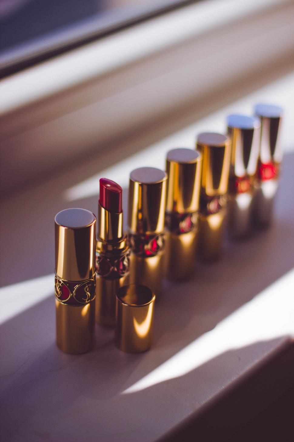 Free Image of Row of luxury gold-cased lipsticks on a windowsill. 
