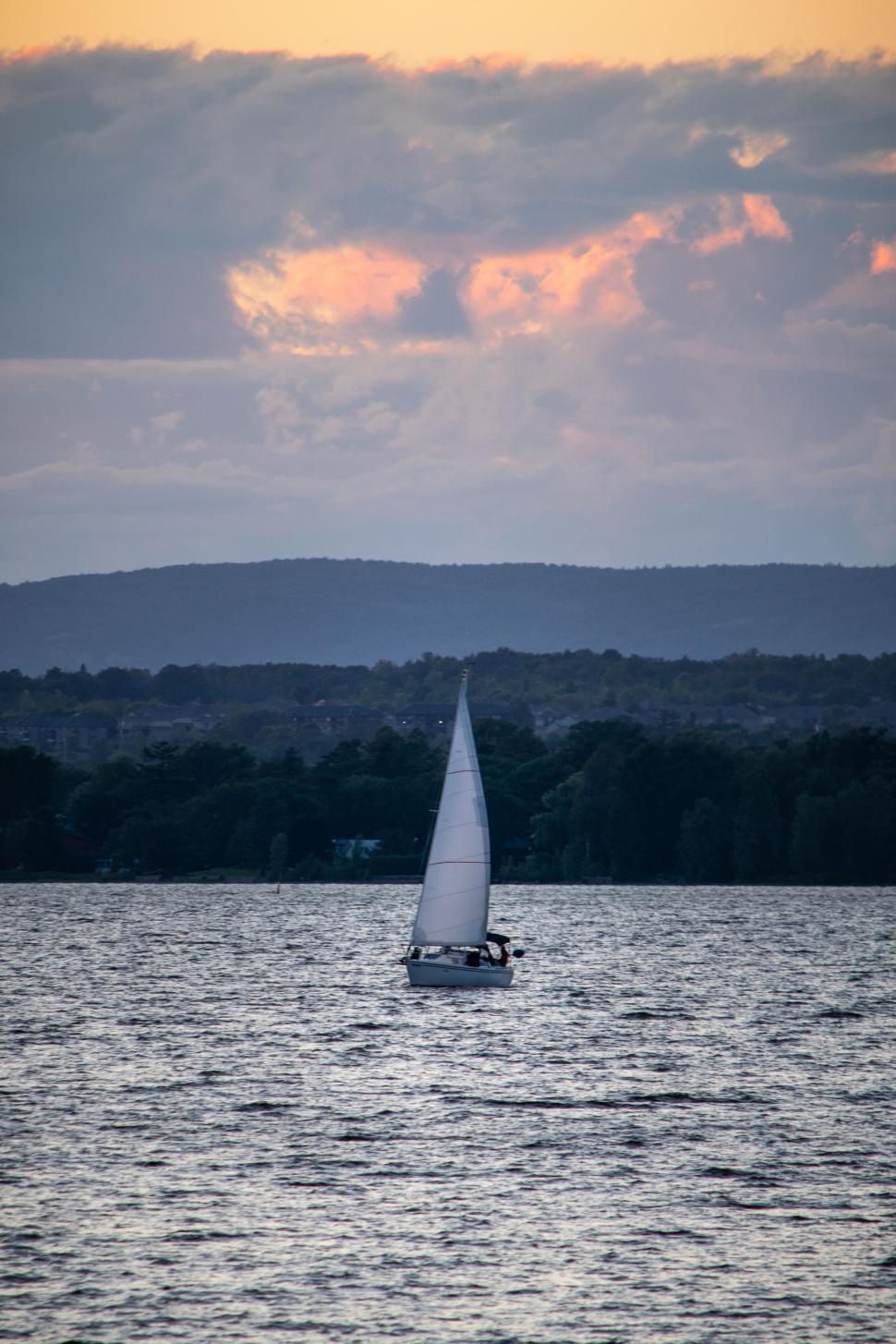 Free Image of Sailboat drifting on calm waters against sunset sky 