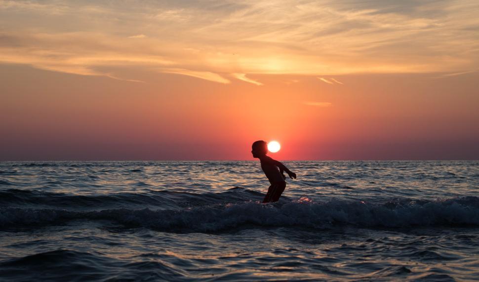 Free Image of Silhouette of person in ocean water during sunset time 