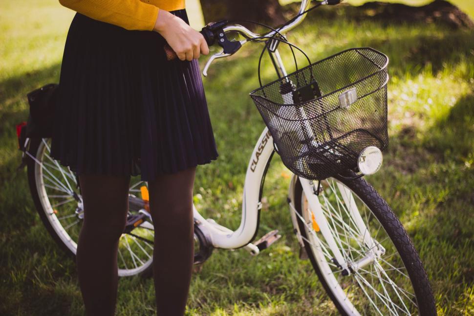 Free Image of Woman in pleated skirt with a bike in the park 