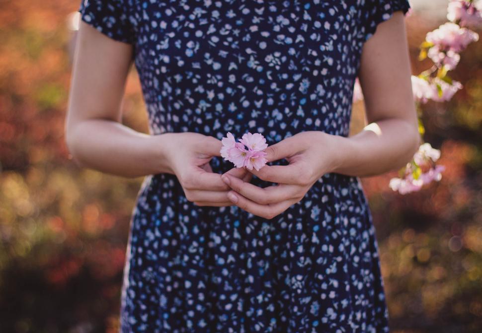 Free Image of Woman holding flowers in a blue floral dress standing 