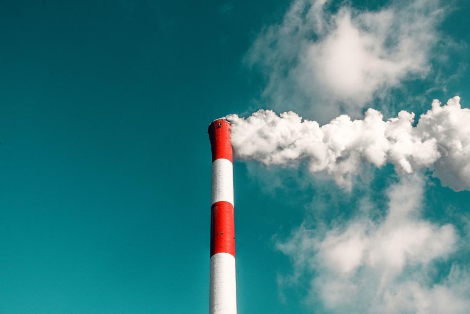 Free Image of Industrial smokestack emitting white smoke against blue sky 