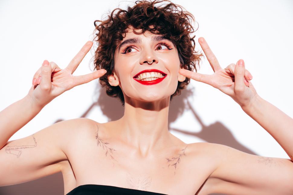 Free Image of Smiling woman with curly hair and red lipstick posing 