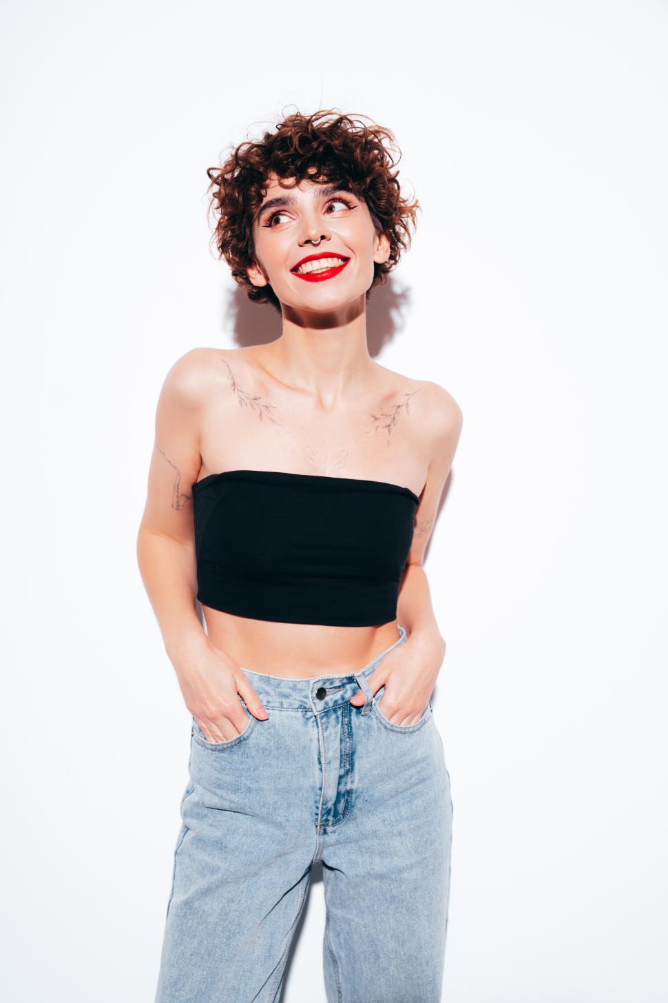 Free Image of Smiling woman in black tube top and casual denim pants 